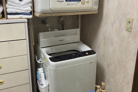 遺品整理前の洗面脱衣室に設置された洗濯機と壁掛け乾燥機の様子（栃木県宇都宮市の2世帯住宅）