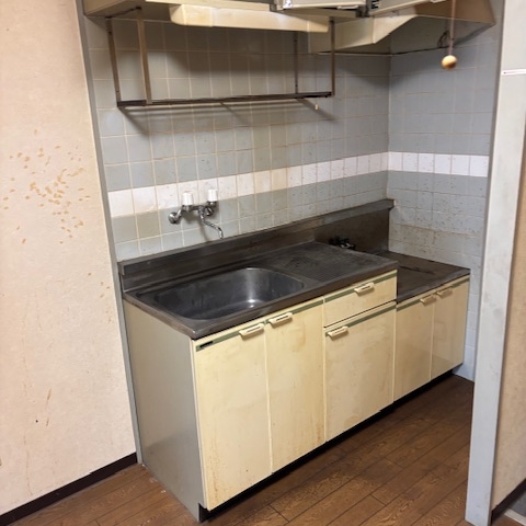 片付け作業後のキッチン全景。不要品がすべて撤去され、収納棚や流し台がすっきりと見える清掃後の状態。