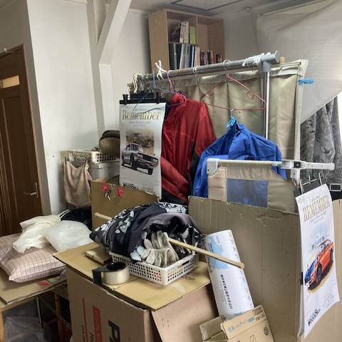 栃木県宇都宮市の集合住宅 片付け前のリビングスペース｜衣類や段ボールなどが雑然と積まれた状態