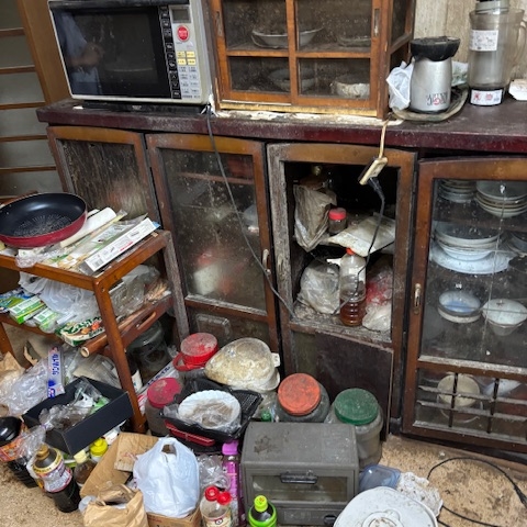 宇都宮市の2世帯住宅1階 キッチンの遺品整理前｜食器棚や調理器具・食品類が散乱している状態