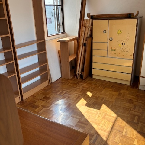 不用品を整理・搬出した後の室内。床が見えるほどすっきり片付き、家具が整然と並ぶ明るい洋室。