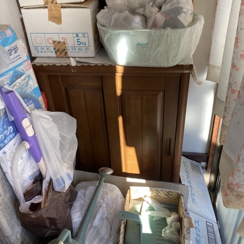 玄関周りに収納家具や雑貨が積まれた状態。