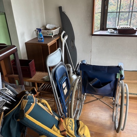 片付け前の洋室。収納の中に衣類や生活用品が残り、室内にも家財が置かれている状態。